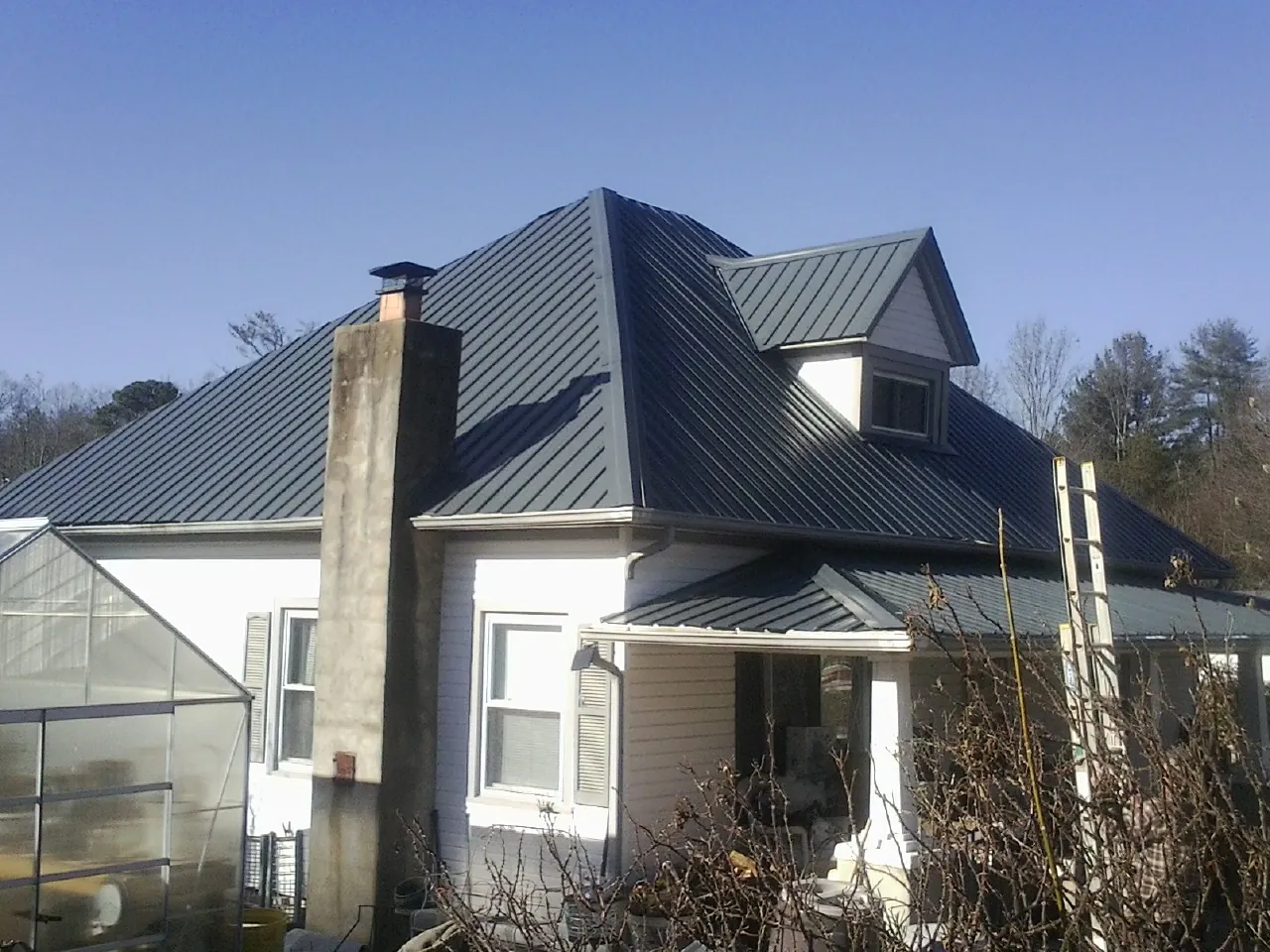 Dark blue standing seam metal roof on a white farmhouse with dormer — Slate & Tile Roof Repair by Roofing Brothers in Fate