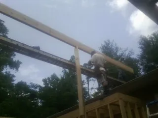 Carpenter setting a ridge beam over a new addition frame — Ice Dam Removal by Roofing Brothers in Fate