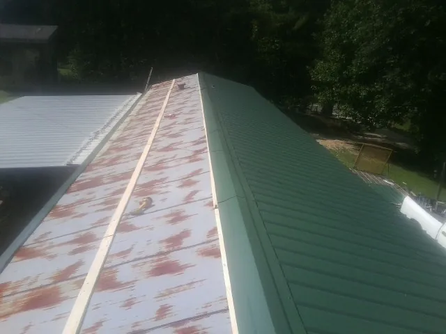 Old rusted panels beside newly installed green metal roofing — Wind Damage Roof Repair by Roofing Brothers in Fate