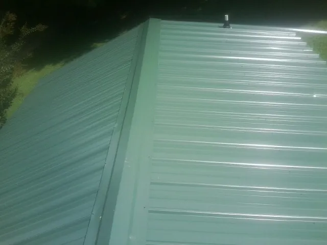 New green metal panels meeting at the ridge of a roof — Flat Roof Repair work by our crew in Fate