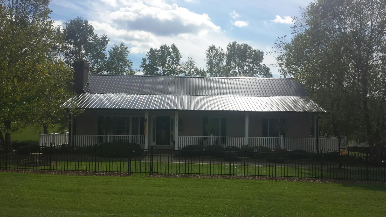 Gray metal roof on a brick ranch with a full width front porch — Gutter Guard Installation work by our crew in Fate